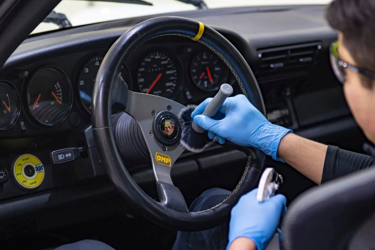 Hender i hansker rengjør rattet i en klassisk Porsche